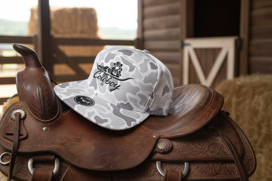 Cowboy embroidered design on a snow camo 7 panel, performance hat.